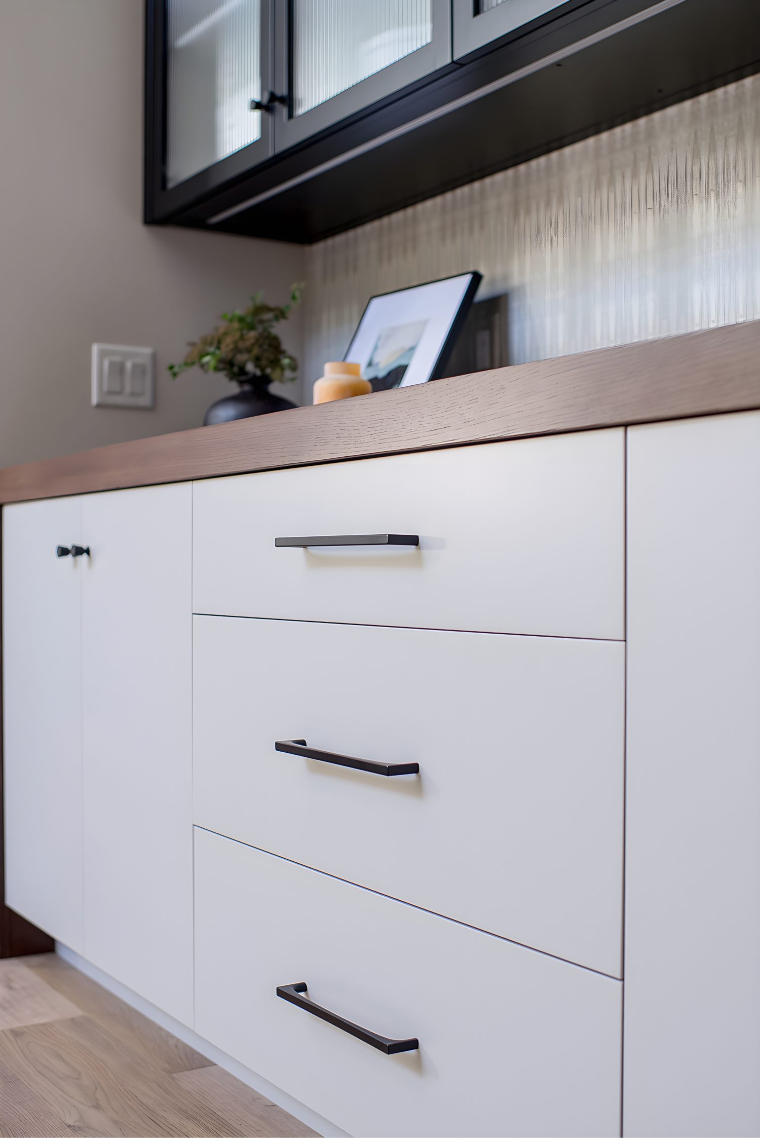 White cabinetry with wood accents, decorative tray, and framed photo