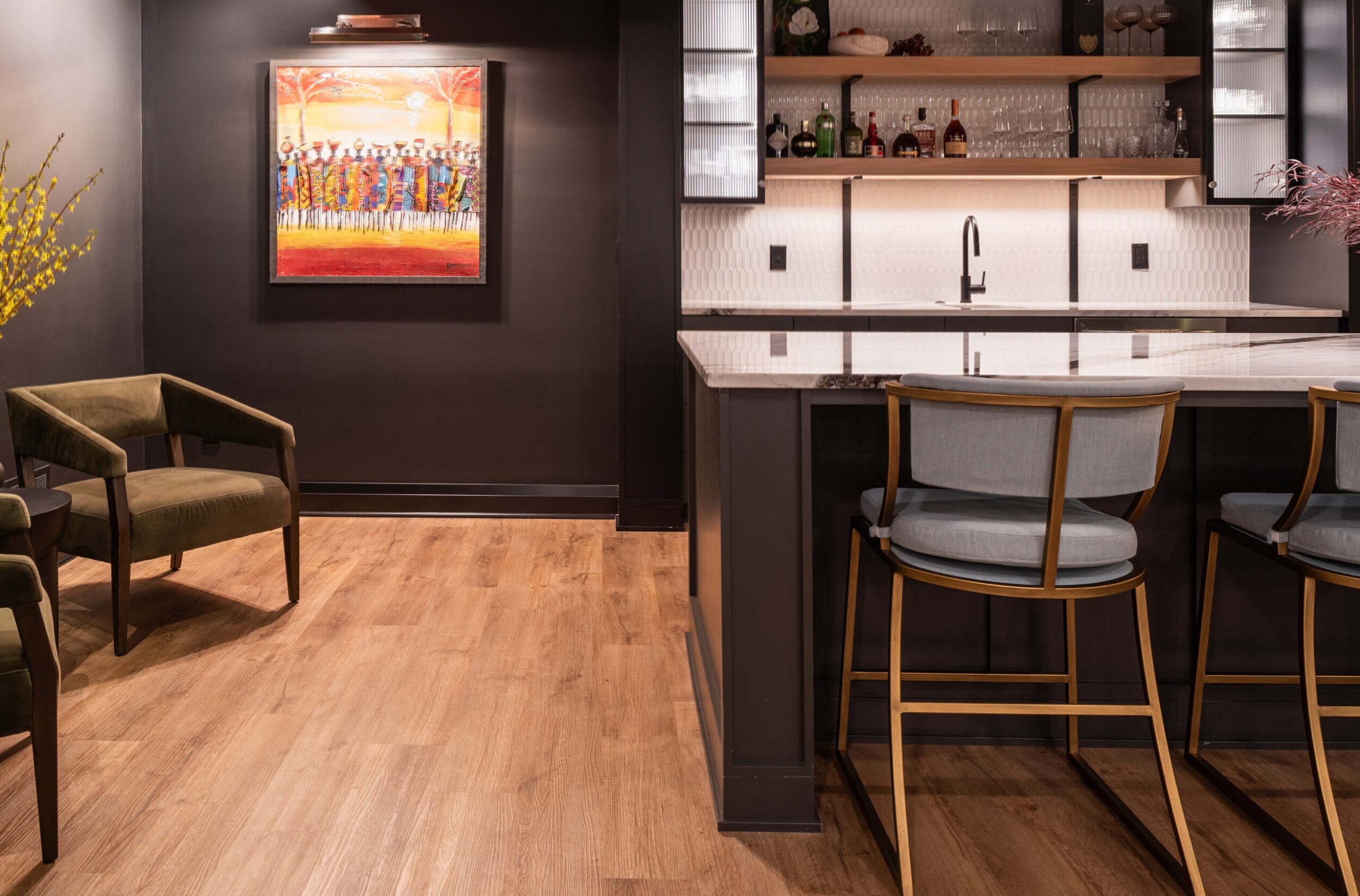 Large marble island kitchen with pendant lighting, bar seating, and modern black cabinetry accented with wood