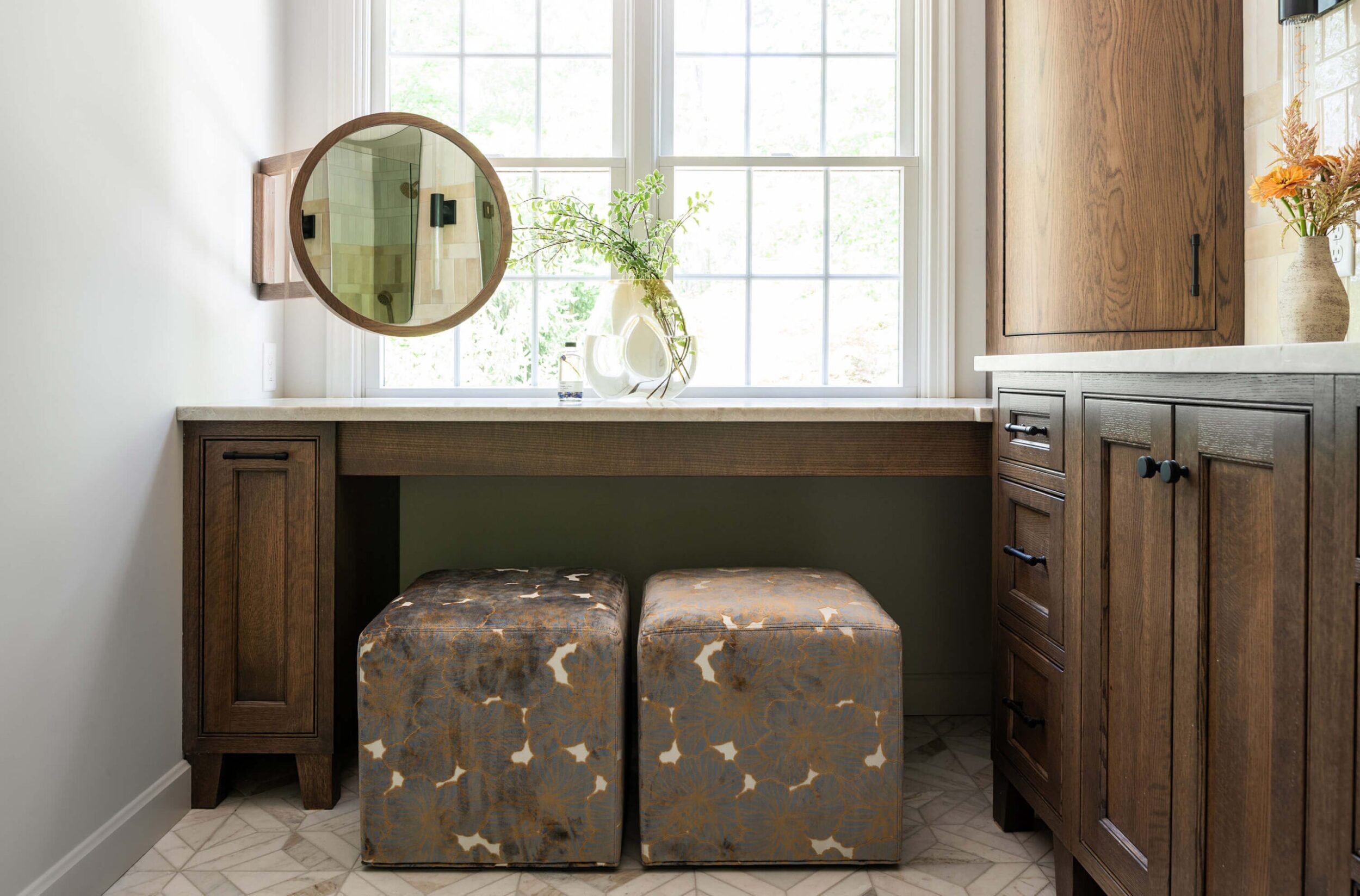 Entryway with dark console table, round mirror, lamp, and books styled against white wall.
