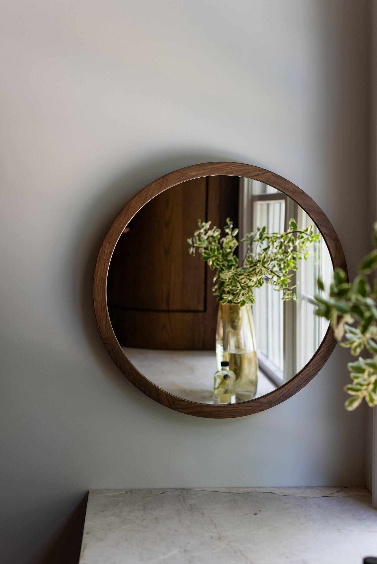 Living room corner with patterned armchair, round side table, and framed art on dark wall.