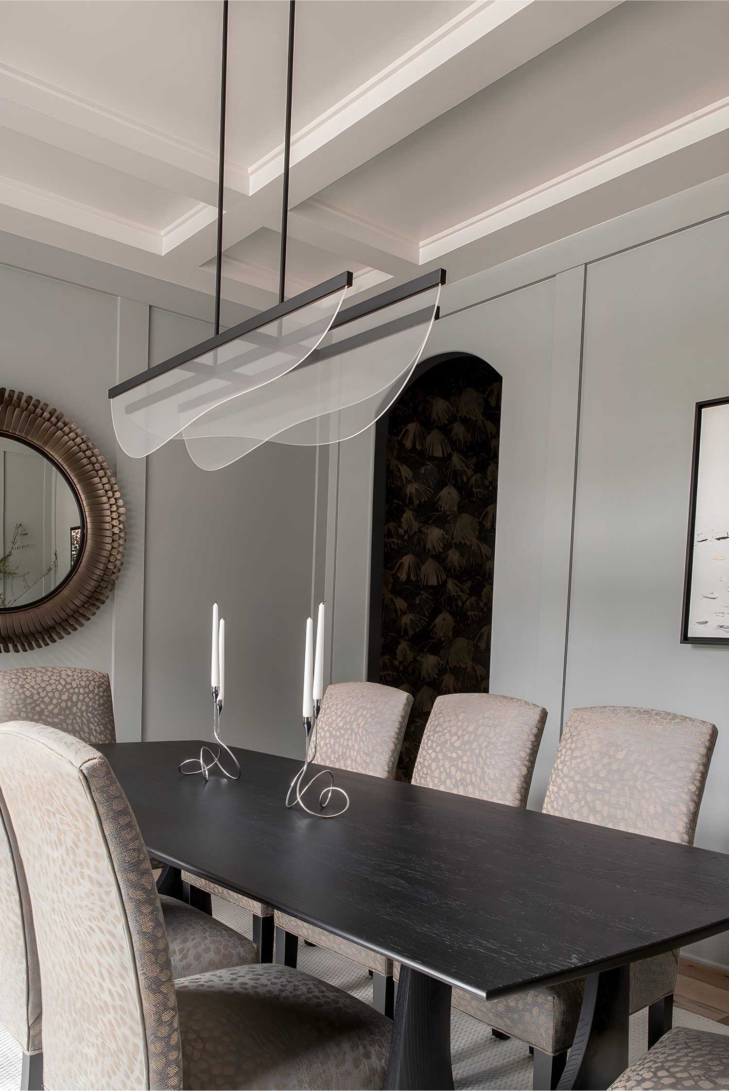 Elegant dining room with long black table, patterned upholstered chairs, and modern linear pendant lighting