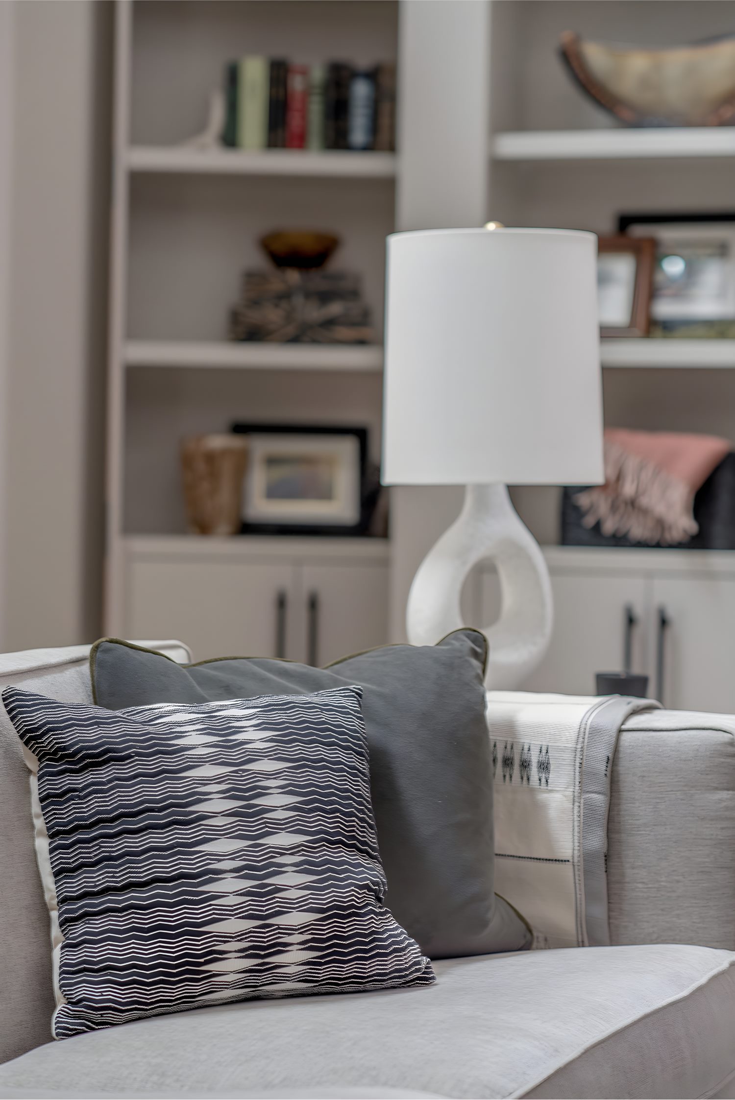 Close-up of a modern sofa with black and white patterned throw pillow in front of built-in shelving décor