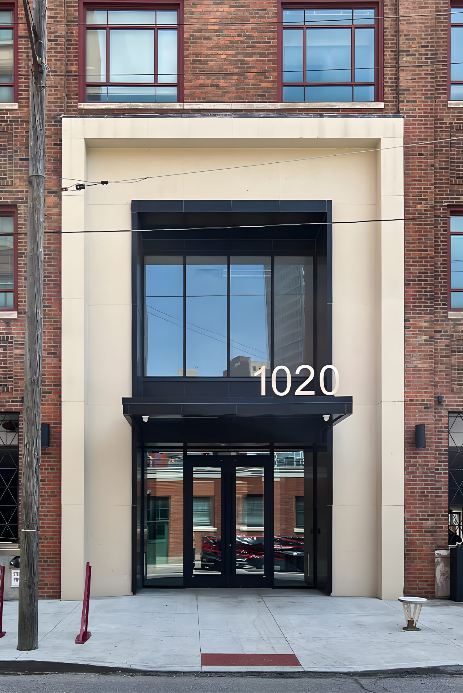 Building entrance at 1020 with glass doors, modern black framing, and red brick exterior.