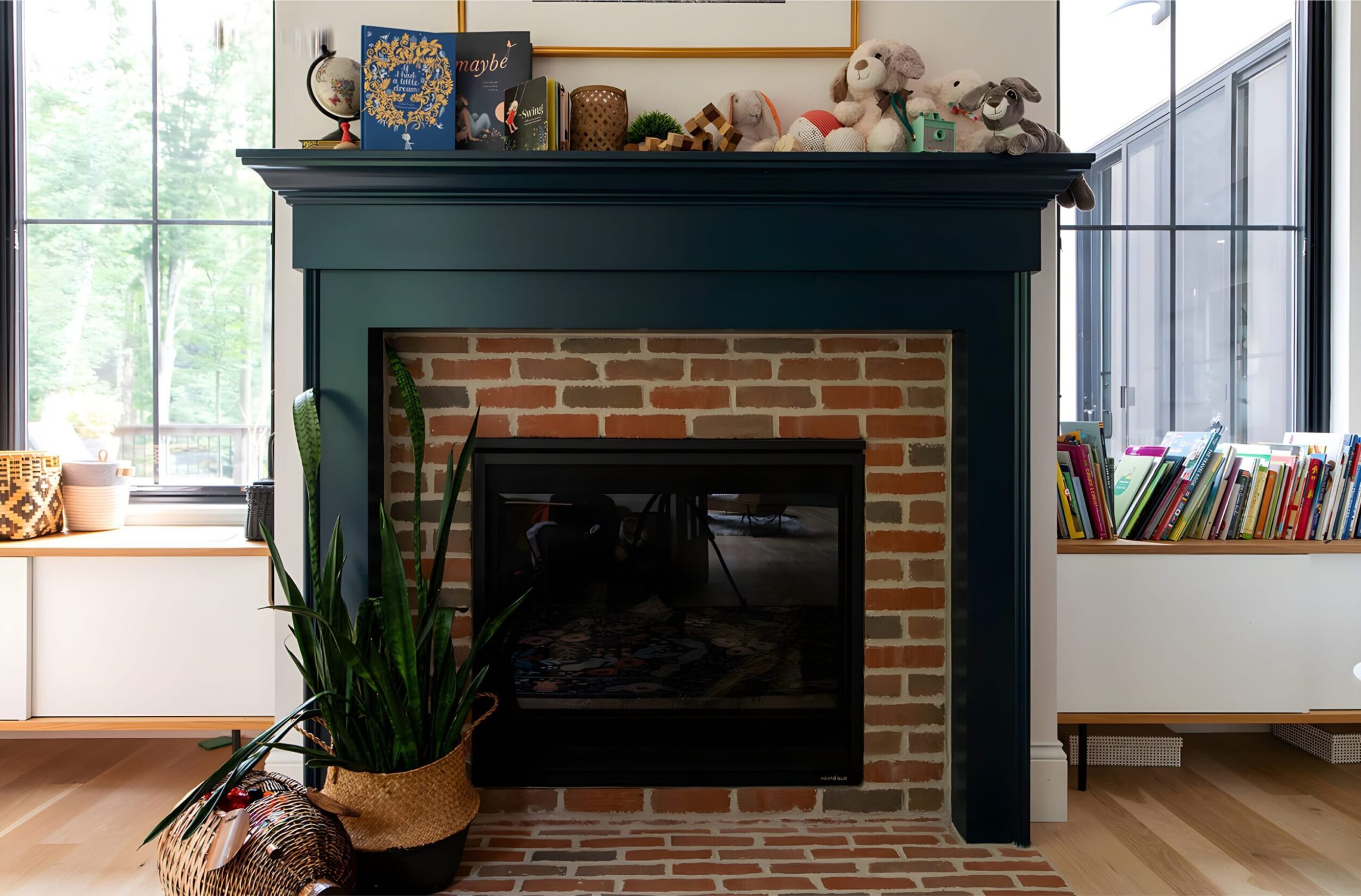 Fireplace mantel with red brick surround, decorated with books, plants, and plush toys in a cozy family space.