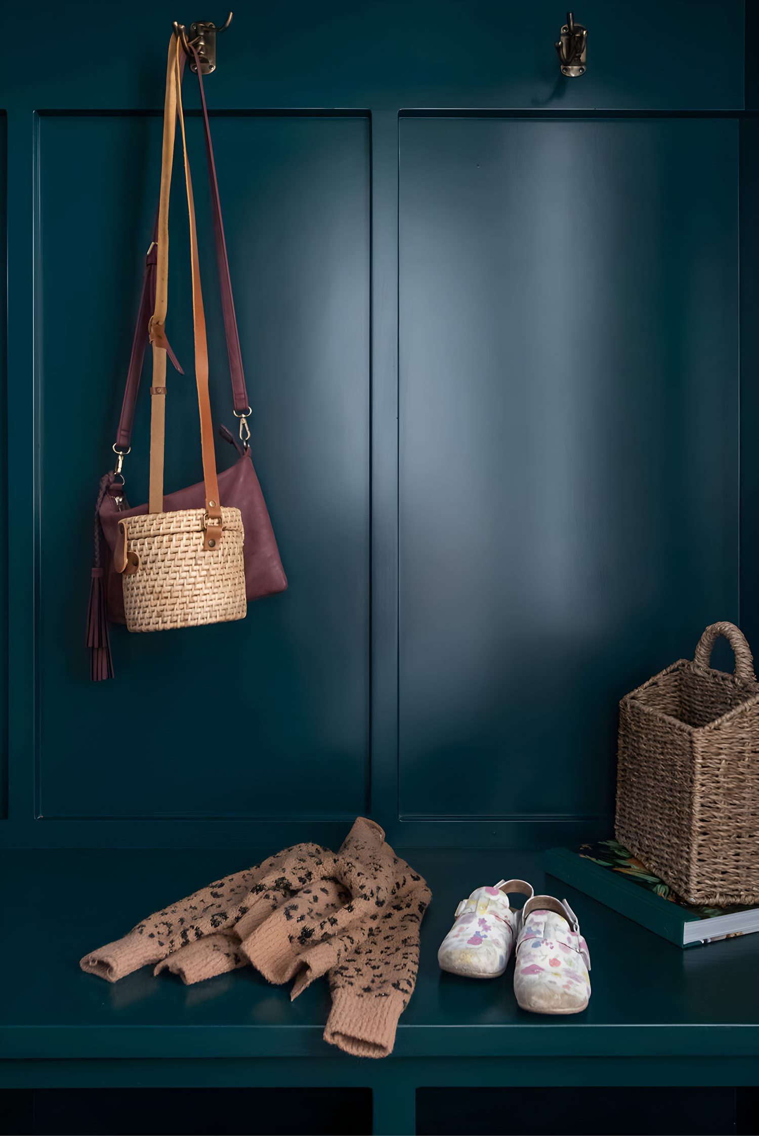 Close-up of teal mudroom bench with woven bags, sweater, floral shoes, and storage basket for daily use.