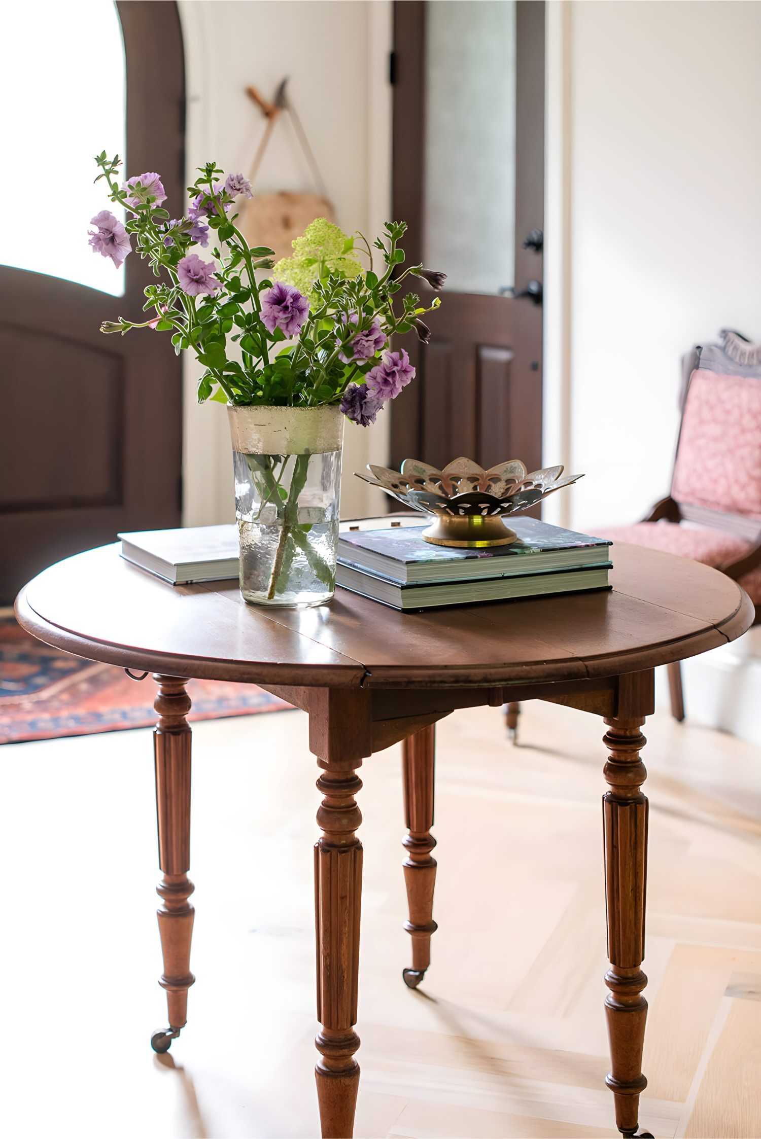 Wooden entry table with vase of flowers and books in bright hallway