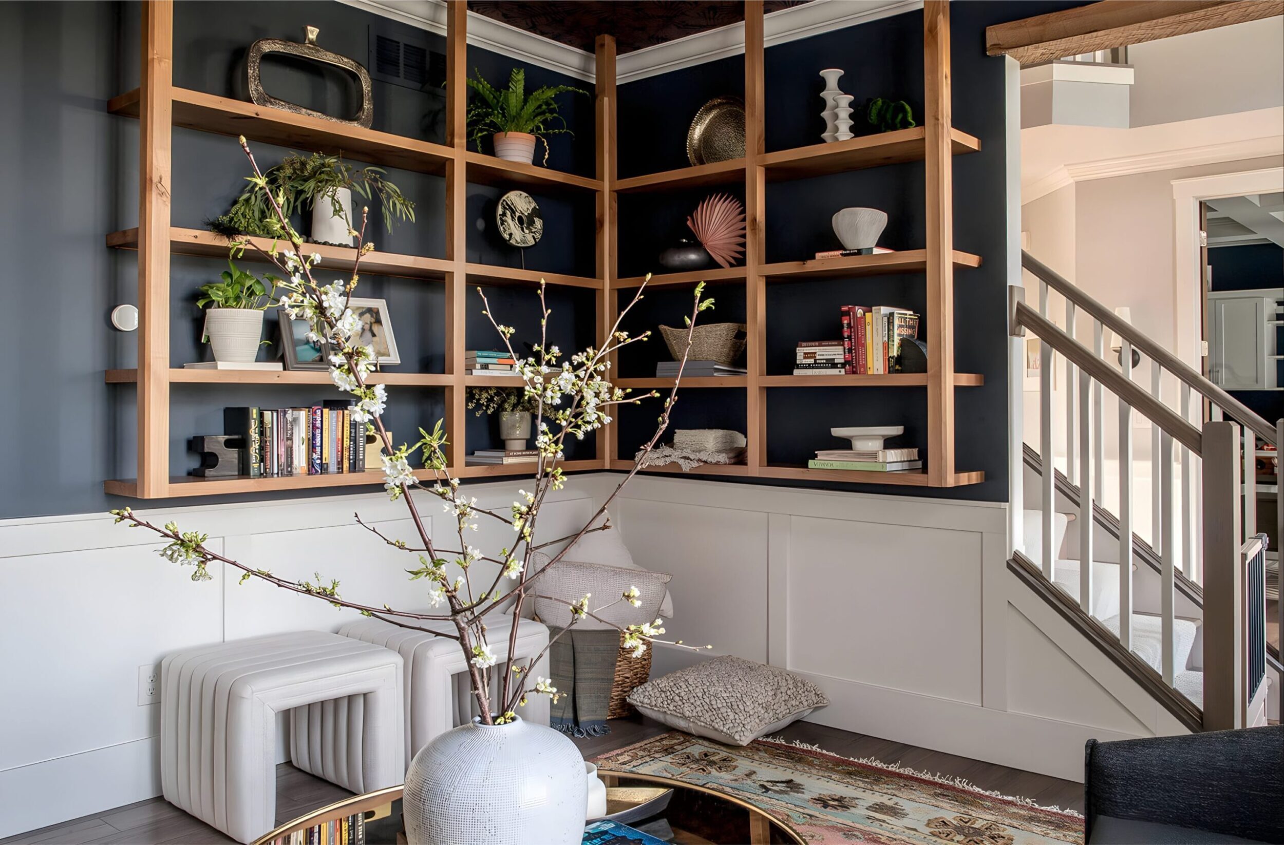 Custom built-in shelving with plants, decor, and books styled alongside seating and floral arrangements.