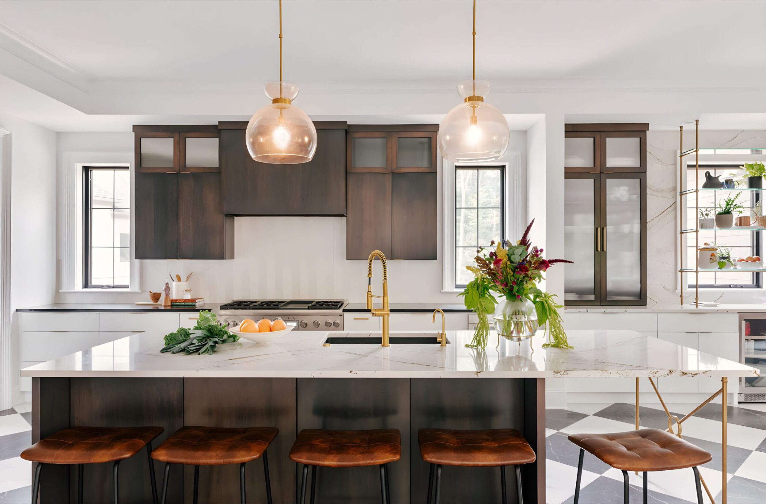 Bright kitchen with marble island, brass faucet, dark wood cabinets, pendant lights, and brown leather counter stools