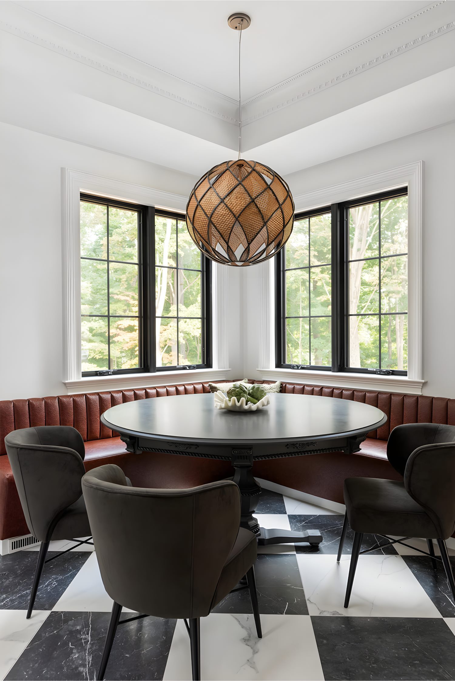 Kitchen corner nook with black round dining table, leather banquette, dark chairs, and large windows with black frames