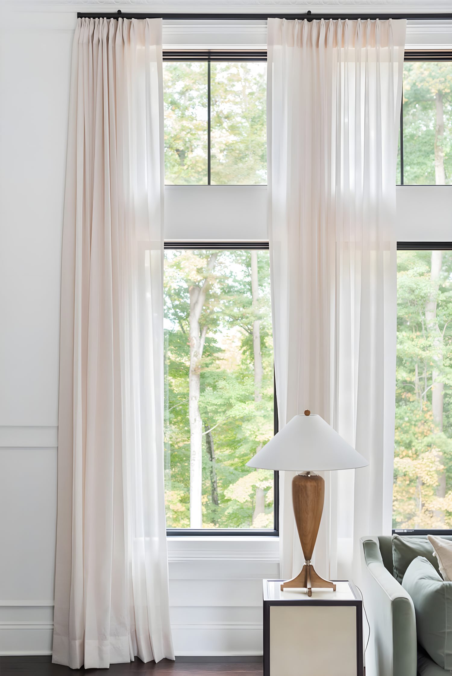 Tall window with sheer white curtains beside modern lamp on side table, soft light highlighting interior textures