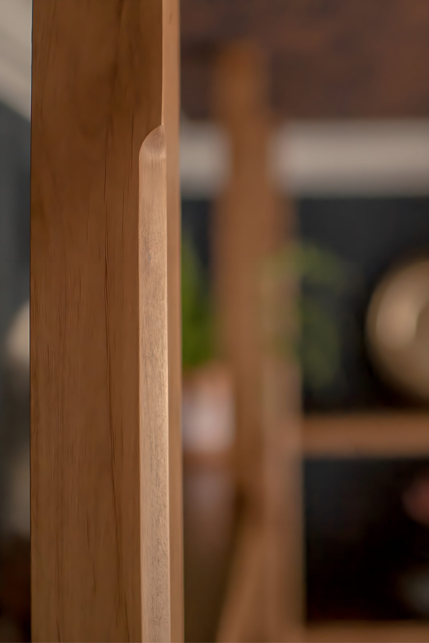 Close-up of custom millwork detail in natural wood finish with blurred background showcasing decor accents.