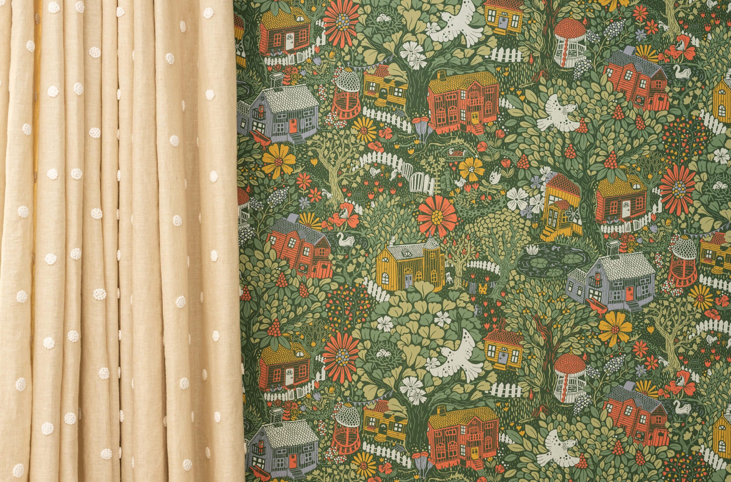 Textured beige curtain with white embroidered dots hangs next to vibrant wallpaper featuring whimsical cottages, flowers, and greenery.