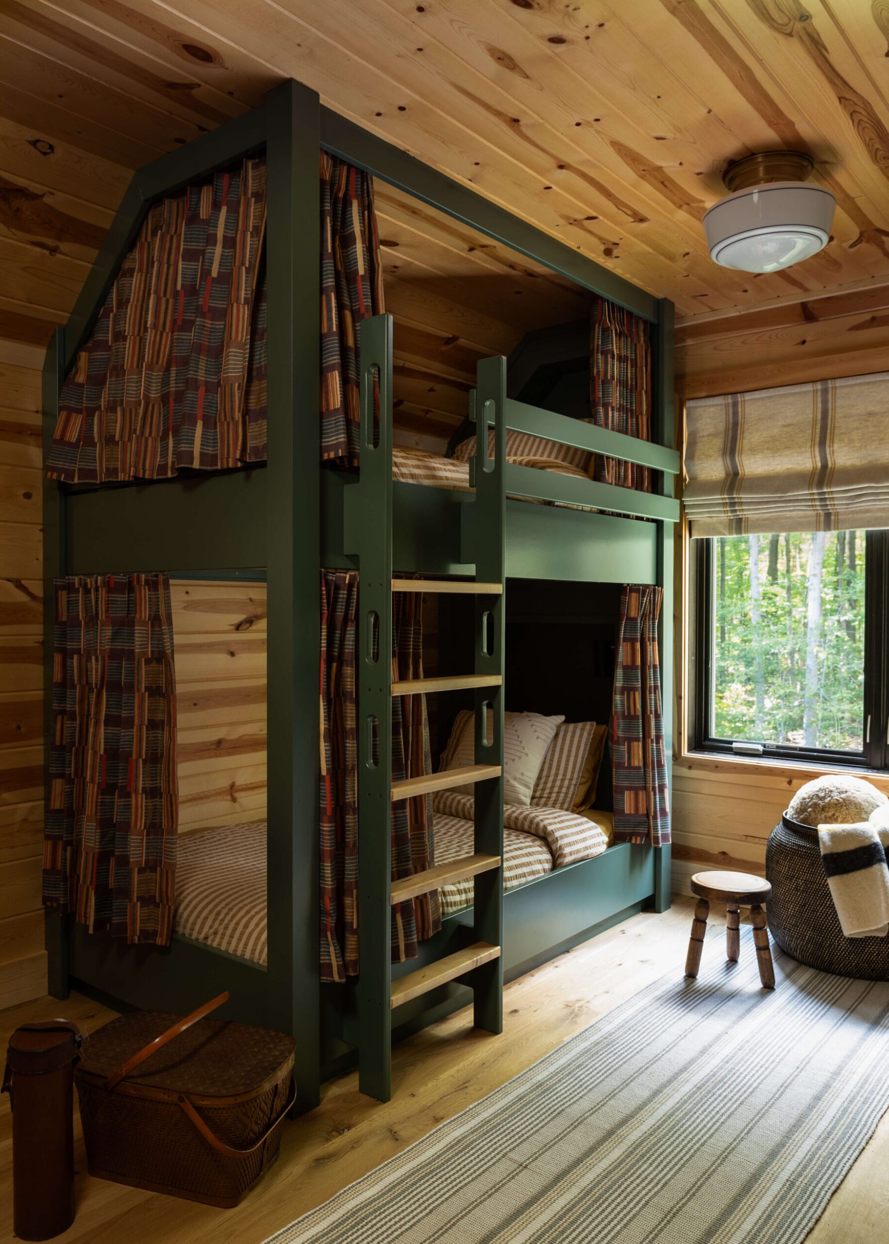 Soft-toned bunk room with built-in twin bunks in sage, layered linens, botanical-patterned curtains, framed wall art and soft light.