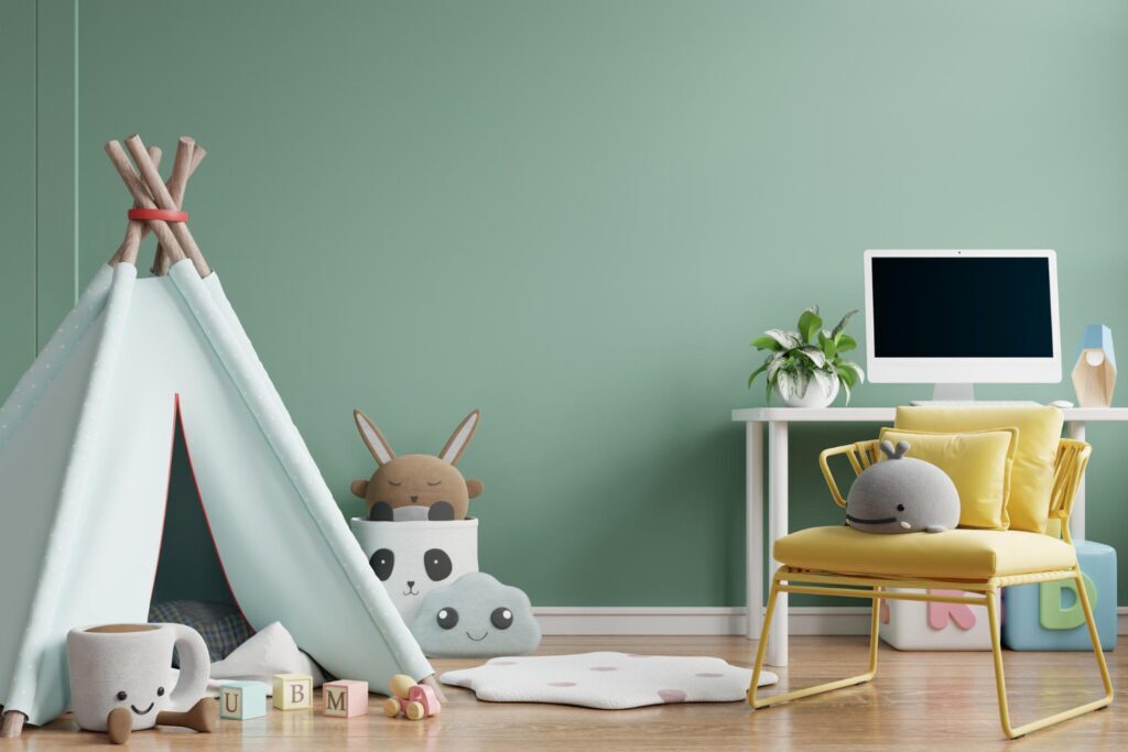 Playful kids’ room with mint green wall, toy tent, plush animals, alphabet blocks, yellow chair, and desk with computer.