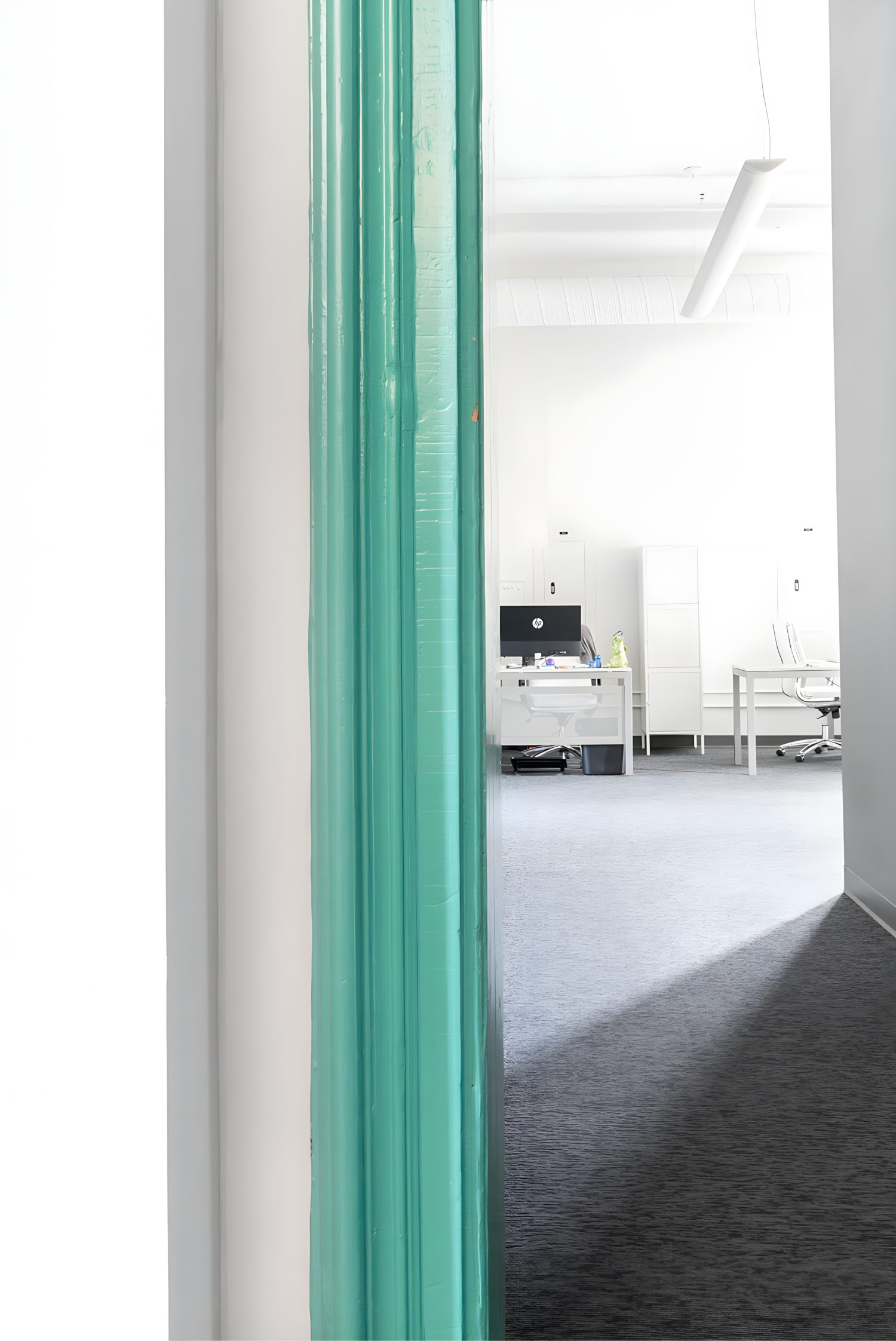Modern office space with glass walls, workstations, and lounge area styled with neutral furniture.