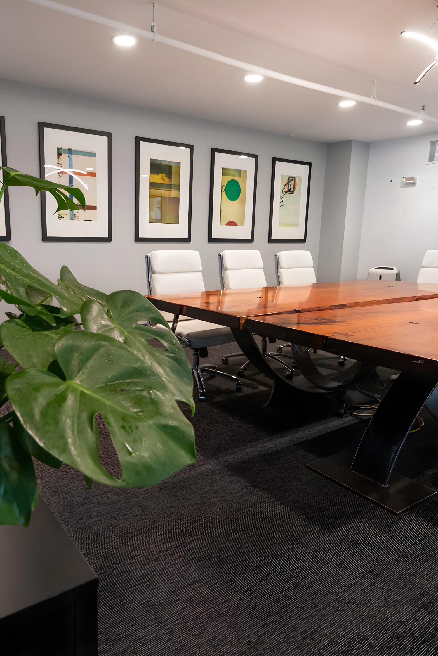 Spacious conference room with long wooden table, leather chairs, and large windows bringing in natural light.