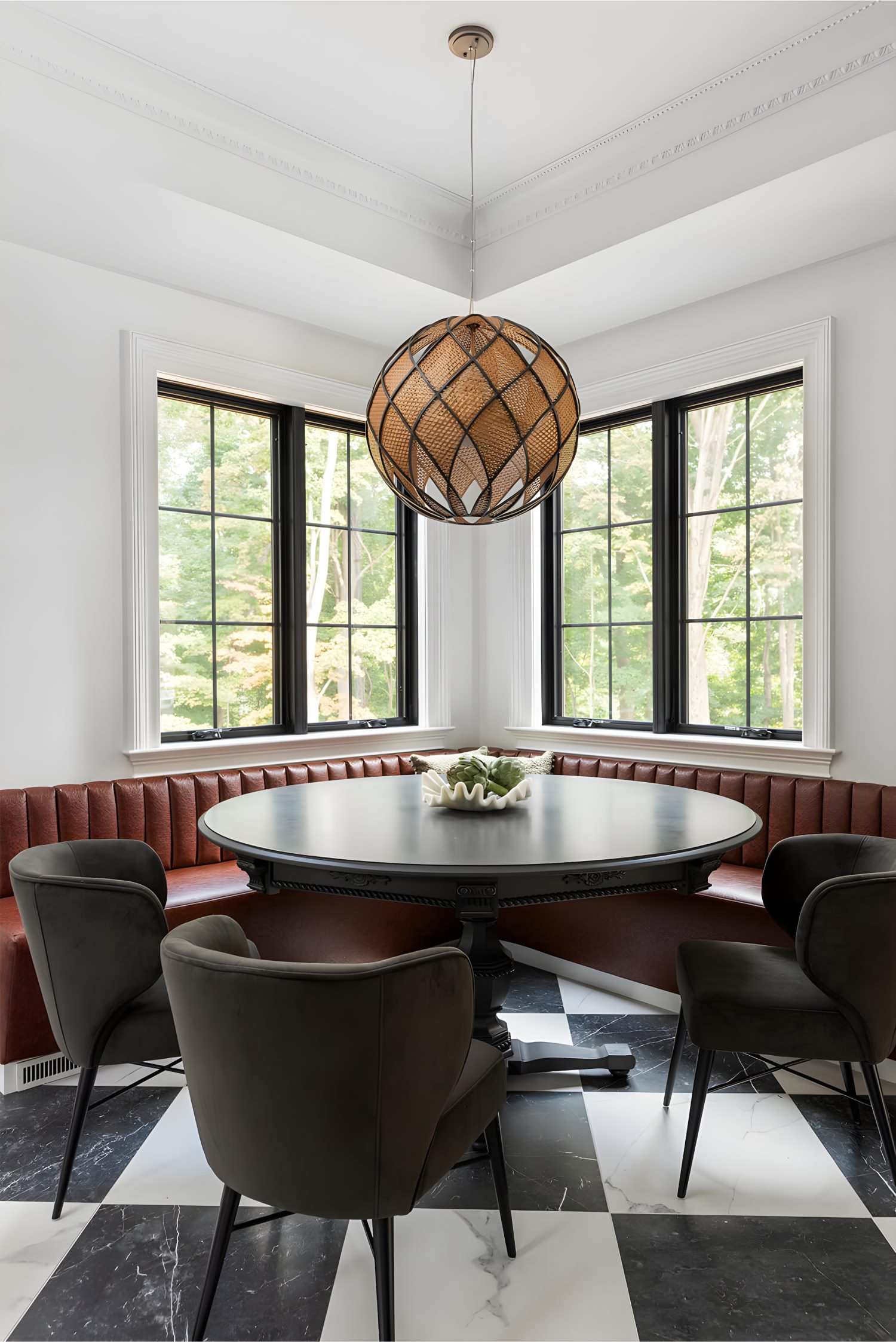 Kitchen corner nook with black round dining table, leather banquette, dark chairs, and large windows with black frames