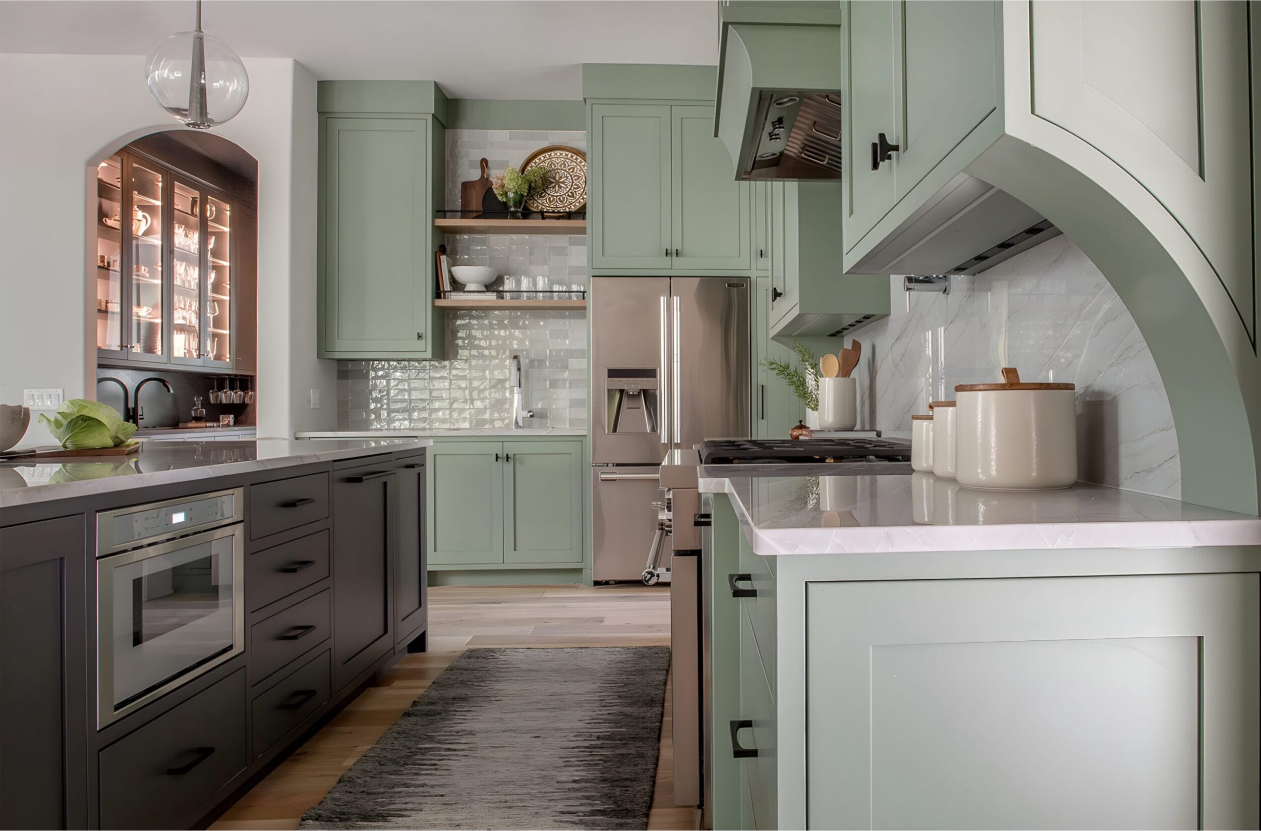 Spacious kitchen with green cabinets, stainless steel fridge, and large island