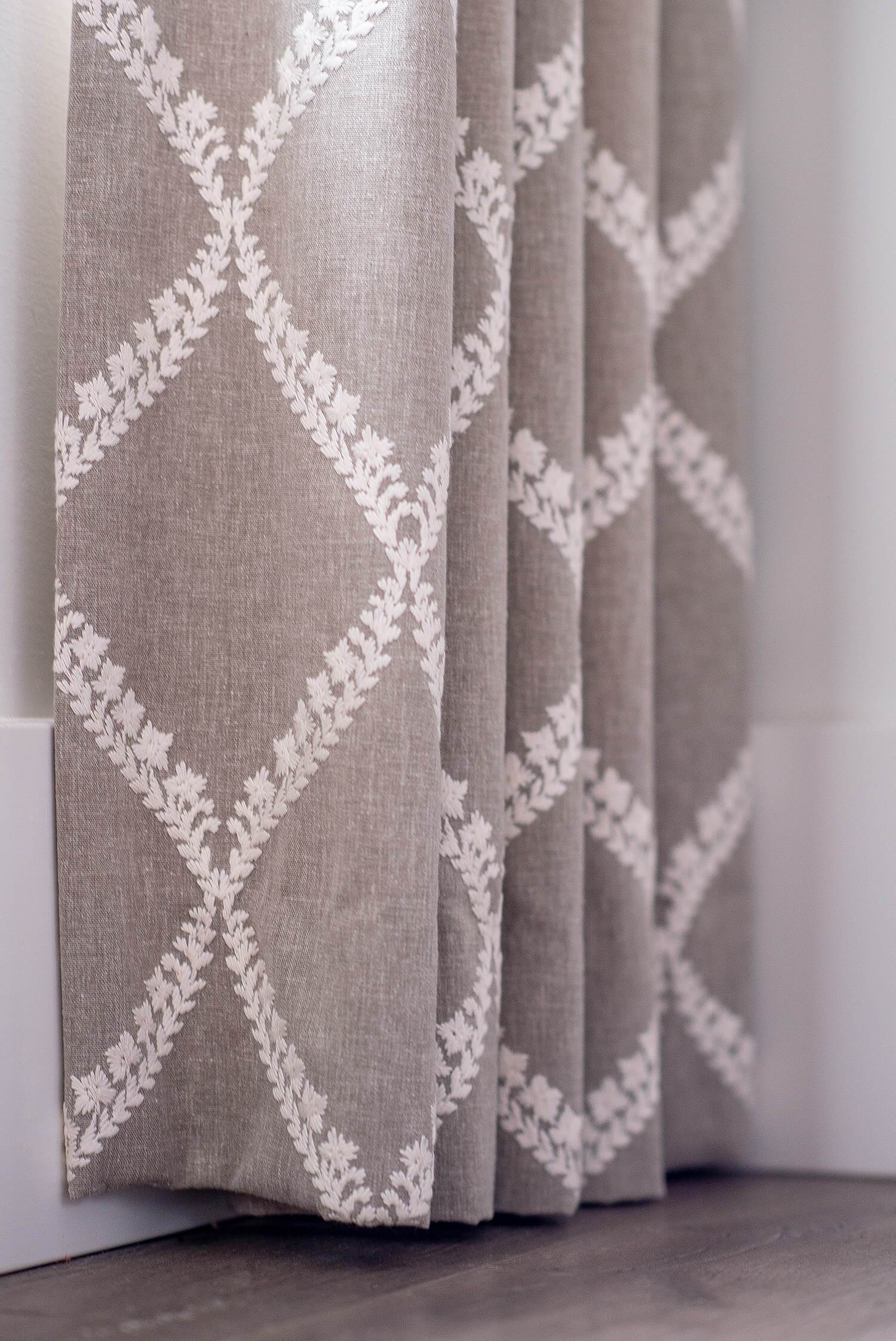 Close-up of taupe curtain fabric with white embroidered diamond pattern detail, styled for an elegant interior finish.