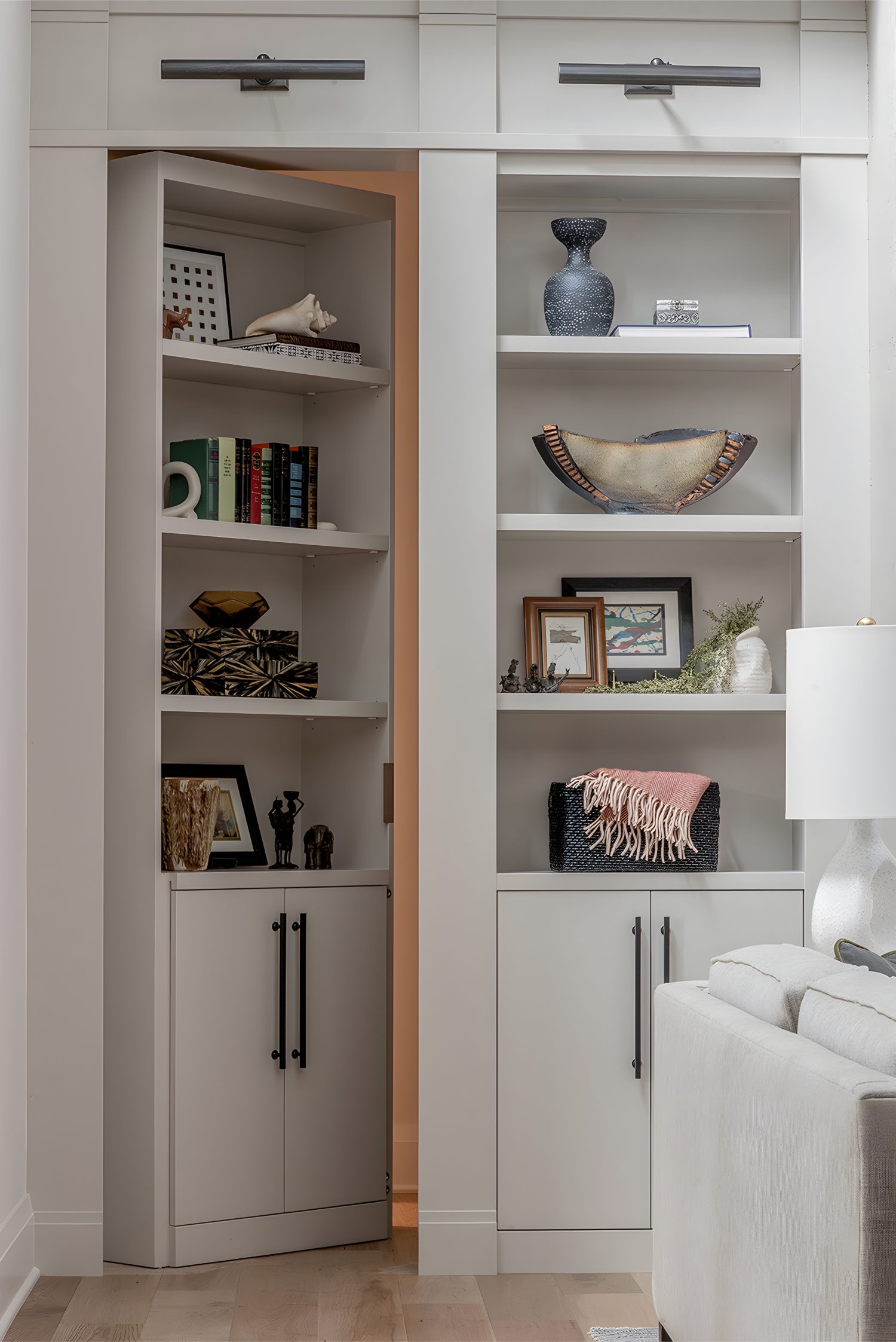 Built-in shelving unit styled with books, art, pottery, and woven baskets in a modern living room corner