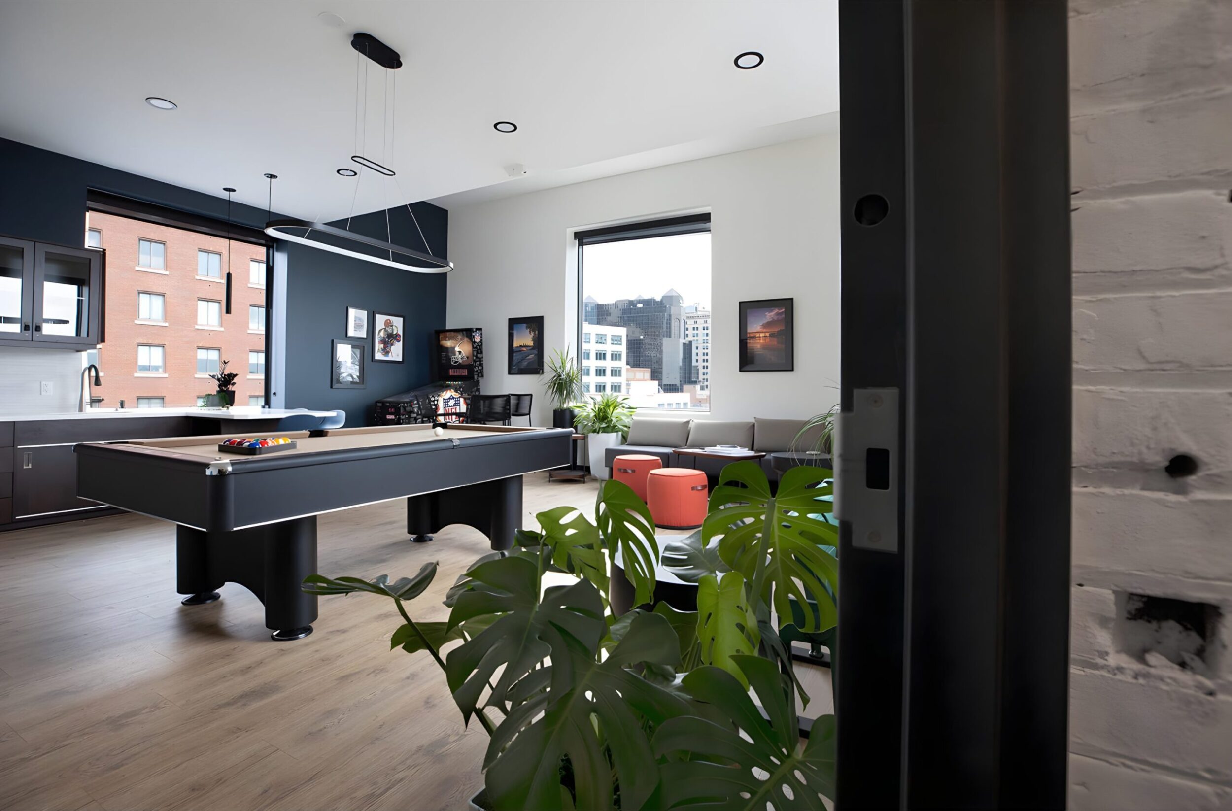 Penthouse lounge with pool table, city views, modern lighting, plants, and wall art accents.