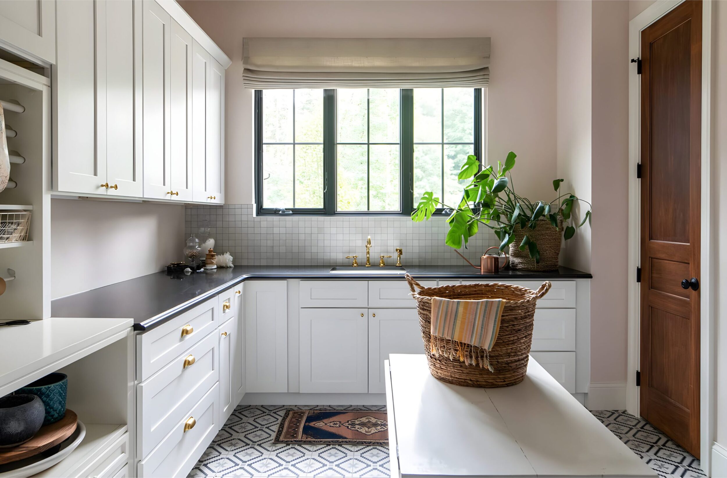Laundry room with white cabinetry, black countertop, patterned tile, and woven basket with striped towel.