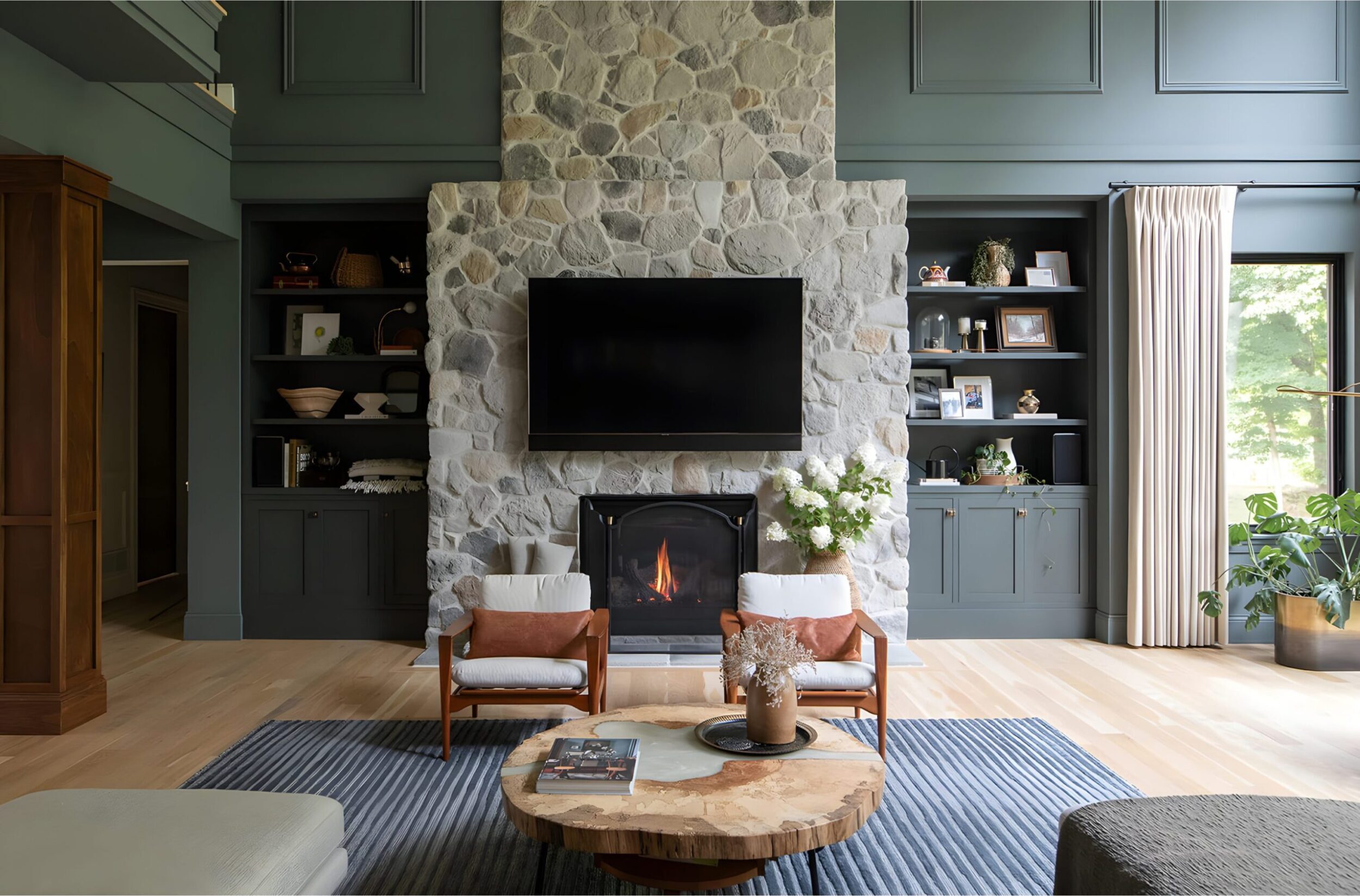 Stone fireplace with mounted TV, armchairs, and built-in shelving in living room
