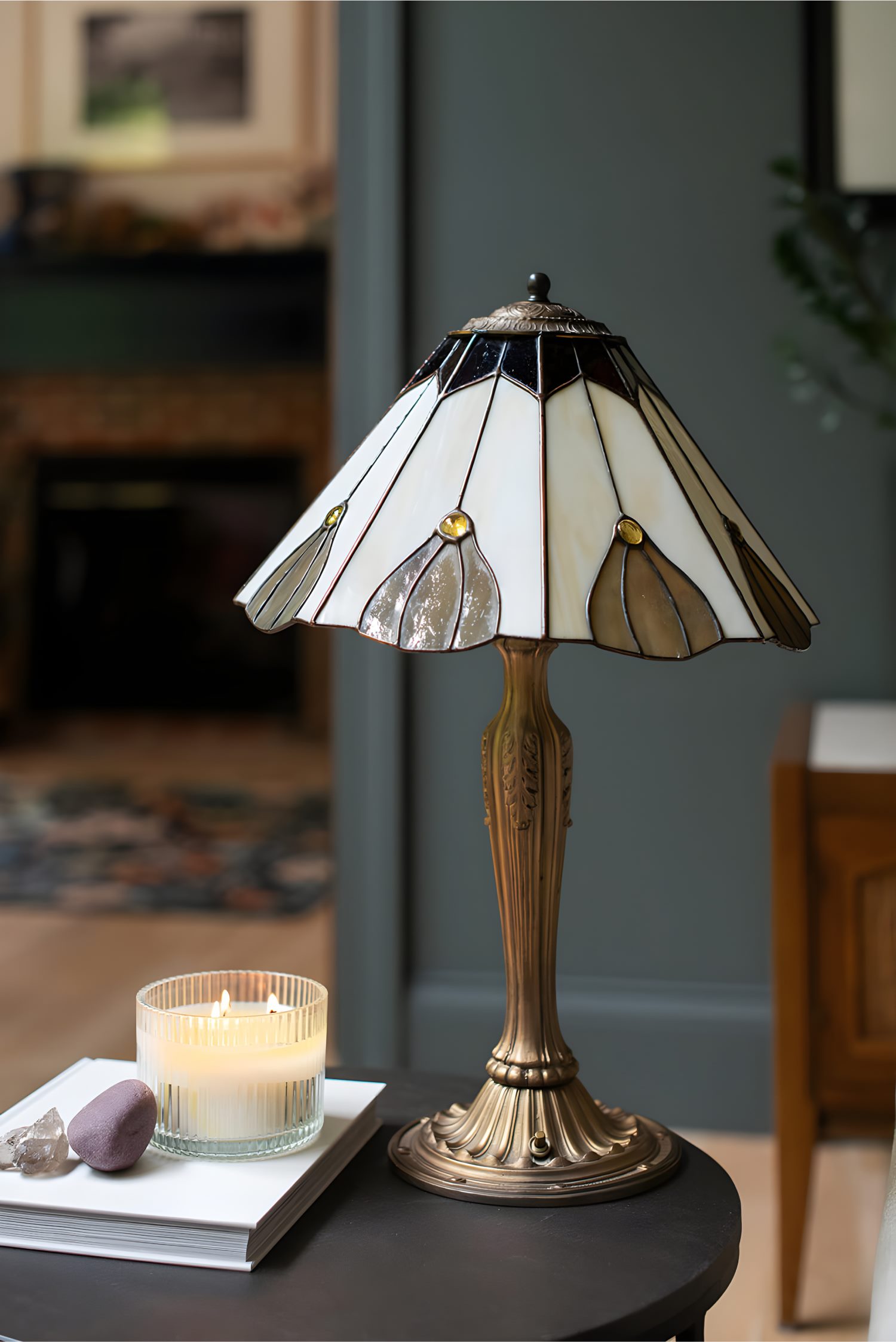 Vintage-style stained glass lamp with lit candle on side table, creating warm and cozy interior accent.