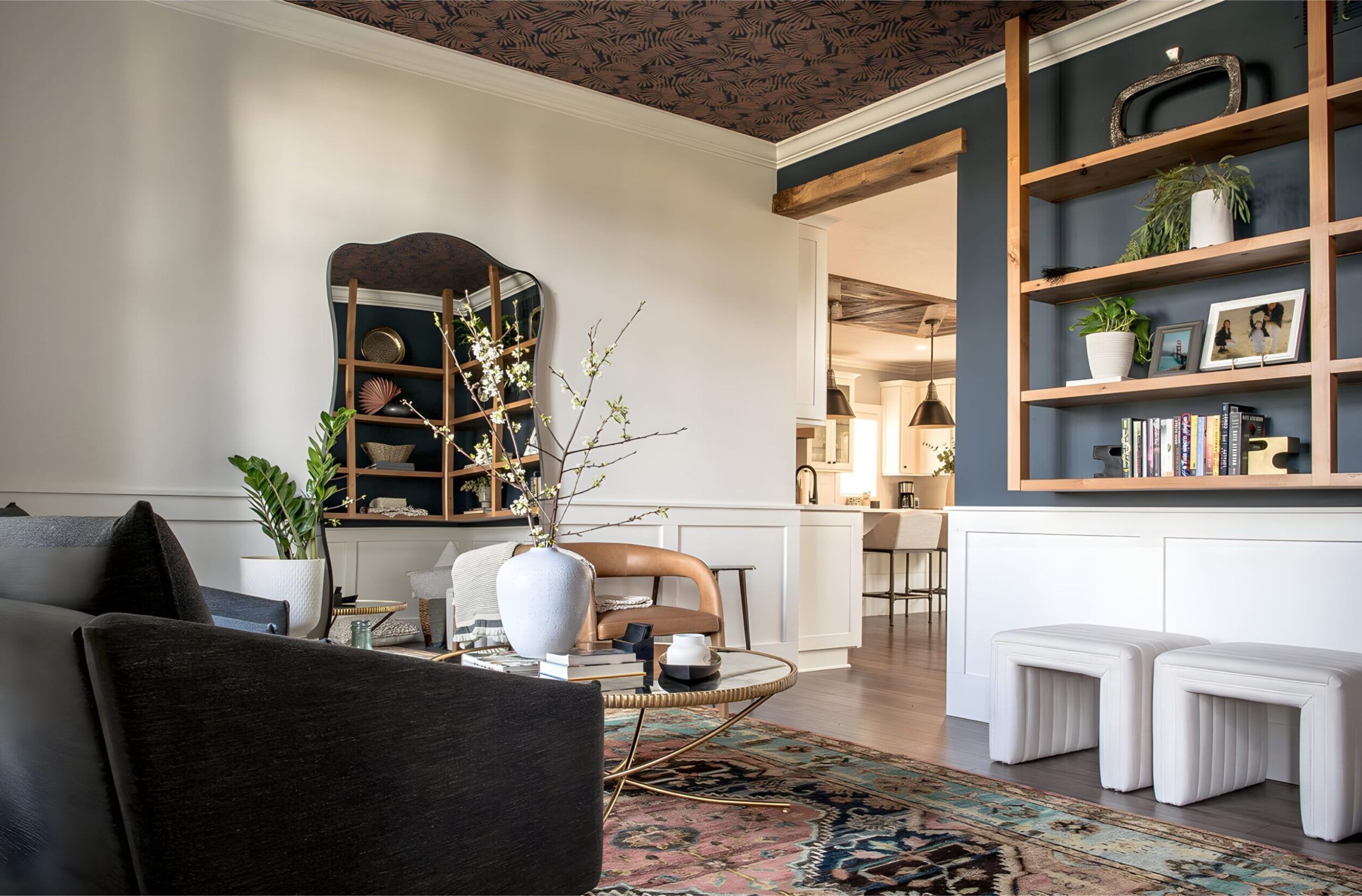 Living room with decorative shelving, large mirror, patterned ceiling, and contemporary furniture styling.