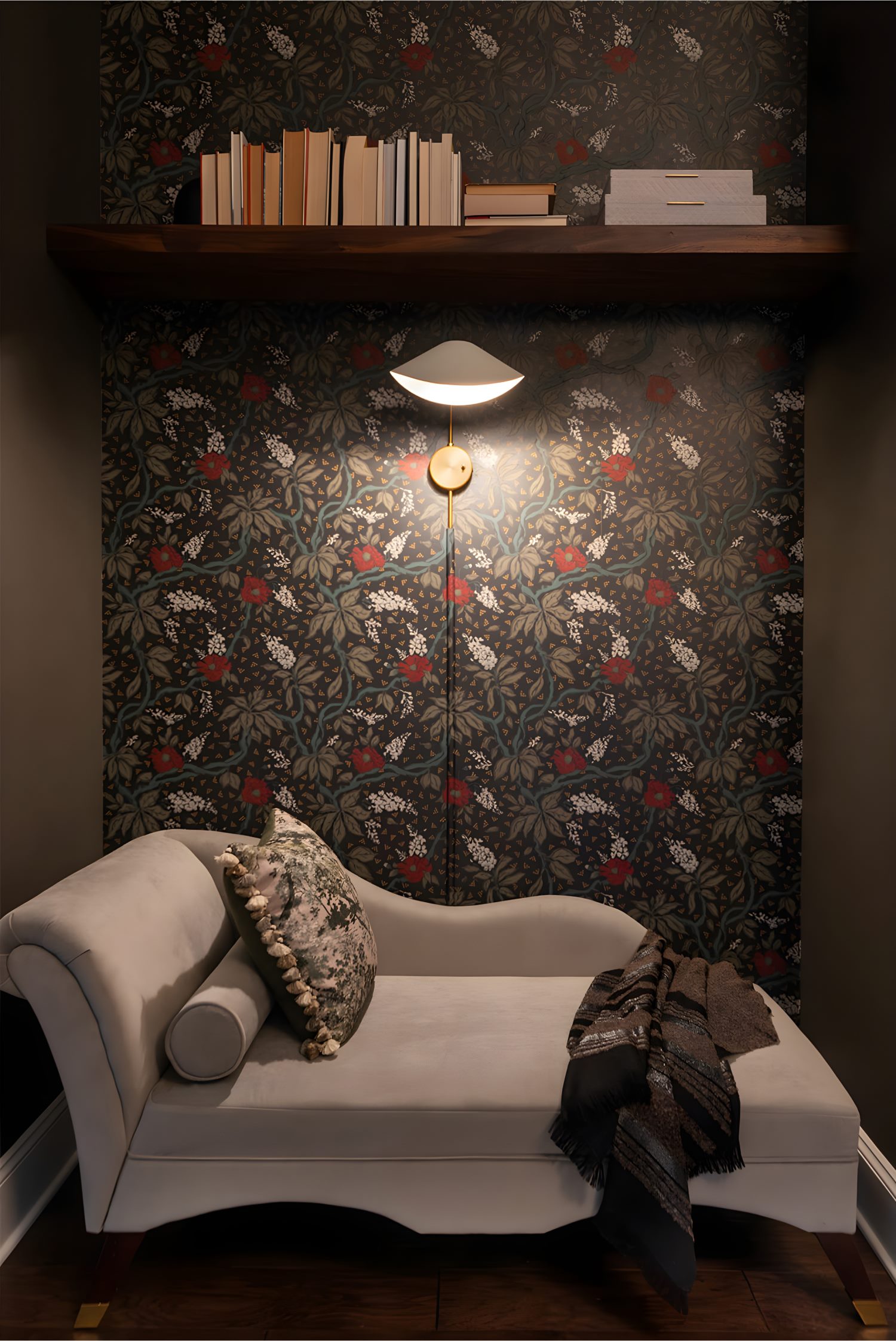 Cozy nook with patterned wallpaper, wall lamp, books on shelf, and a white chaise lounge with pillow and throw