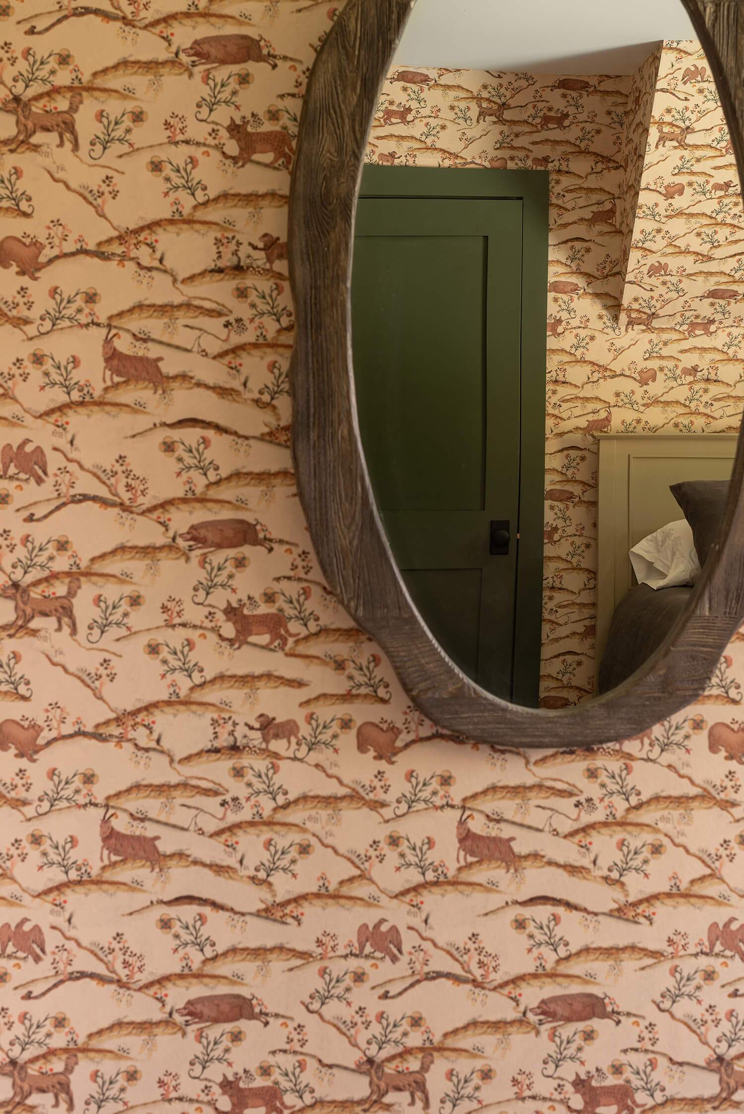 Rustic cabin wallpaper with woodland animals reflected in an oval wood-framed mirror
