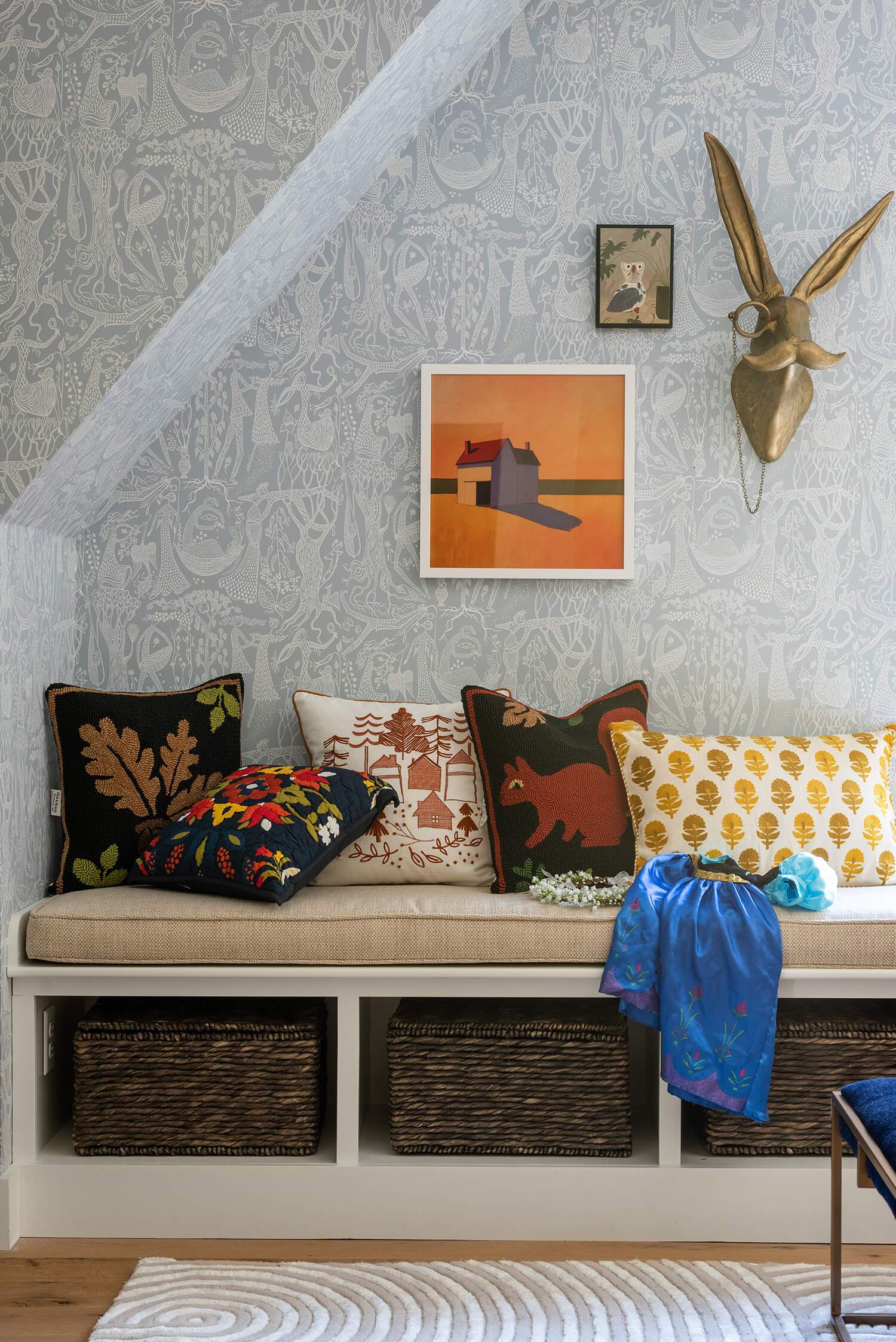 Detailed view of patterned wallpaper, decorative pillows, and wall art in a cozy kids’ lounge corner.