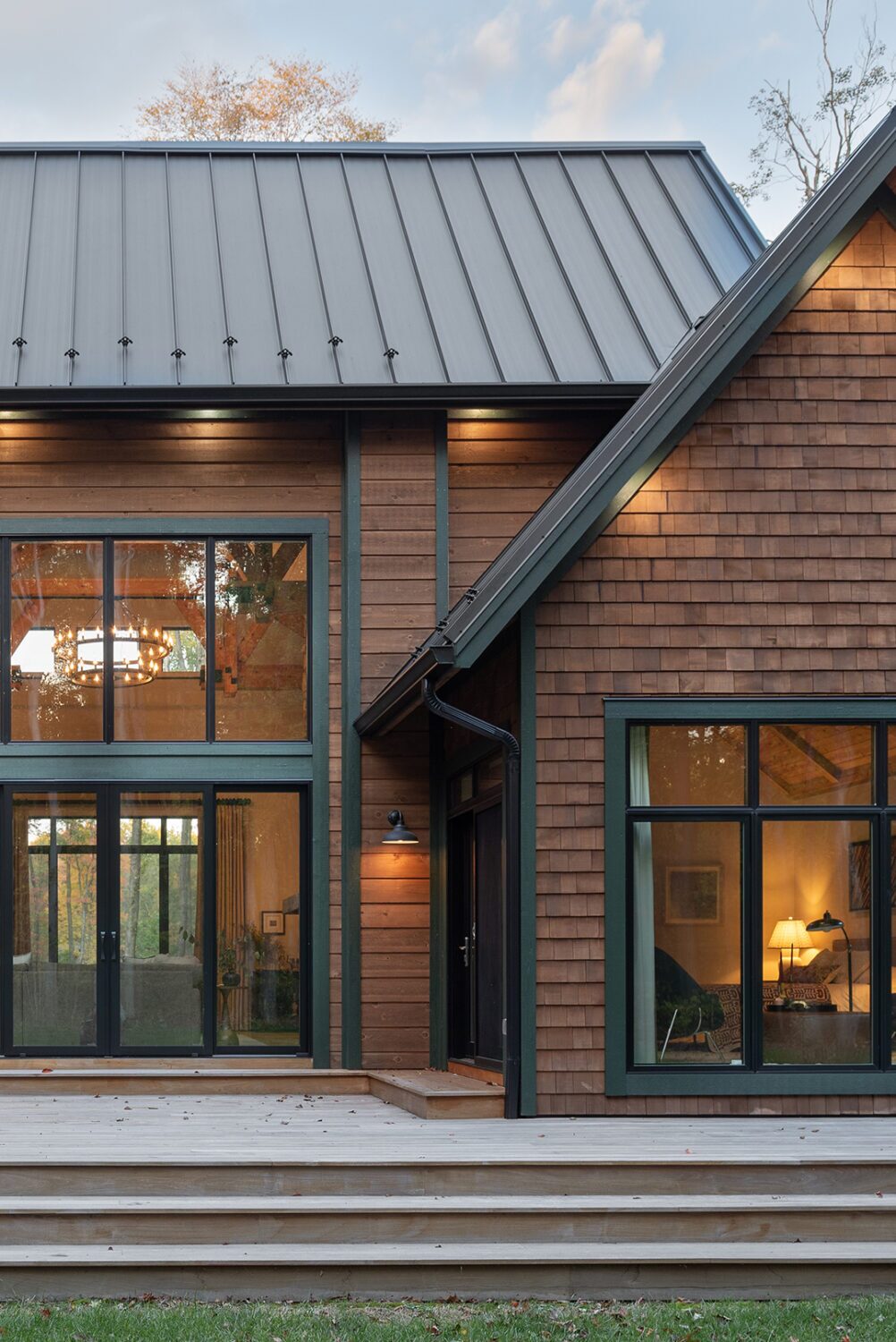Modern cabin exterior with wood siding, black-framed windows, and deck entrance
