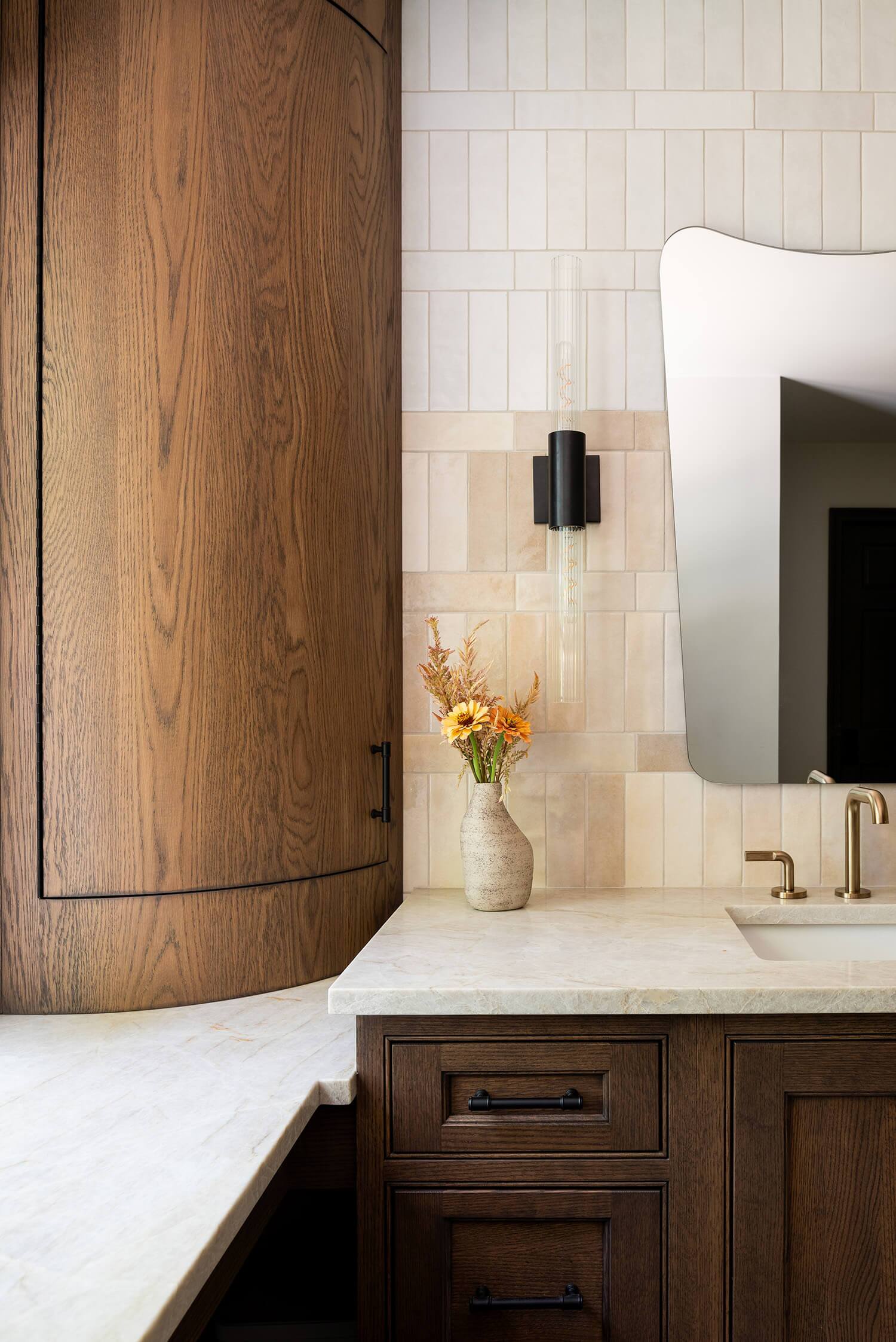 Kitchen view with farmhouse sink, dark cabinets, gold faucet, and open shelves styled with decor.