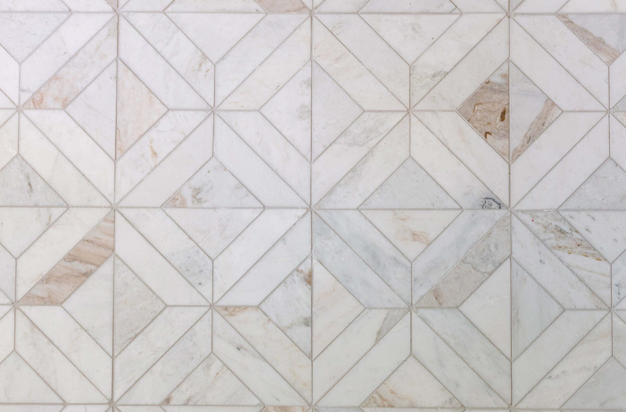 A close-up of a marble Wall with a diamond-patterned tile design in white and beige tones.